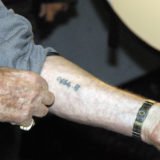 Holocaust - Überlebender zeigt seine Hand mit tätowierter Nummer