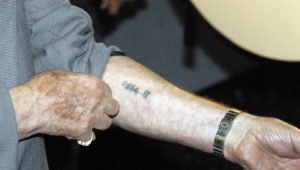 Holocaust - Überlebender zeigt seine Hand mit tätowierter Nummer