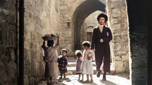 Young Jewish man walking past a group of children in the alleys of the Old City, in the mid-1920s.