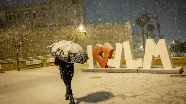 A man walks in the snow near Jerusalem's Old City walls, January 26, 2022.