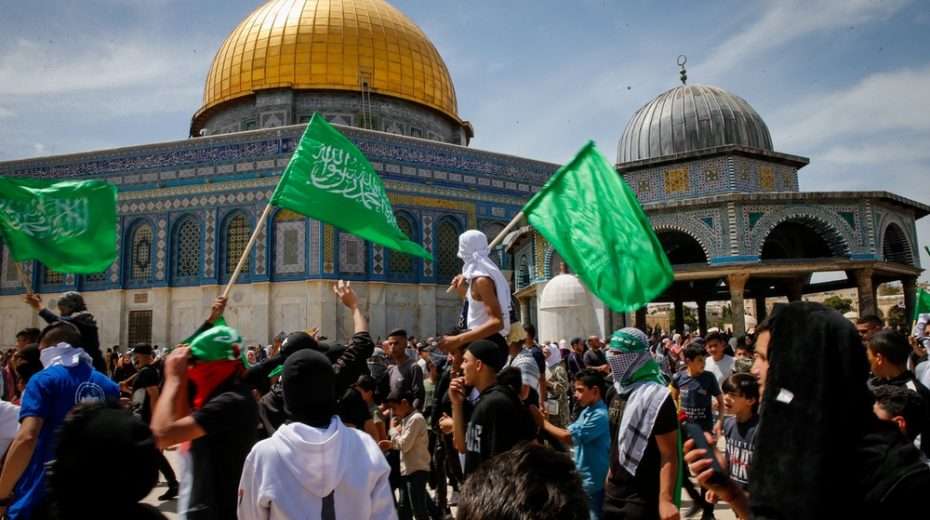 Palestinian Muslims wave Hamas flags while attacking Israeli police and Jewish worshippers from atop the Temple Mount in Jerusalem.