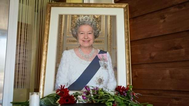 A portrait of Queen Elizabeth II and flowers at the entrance to the British embassy in Tel Aviv on September 9, 2022.