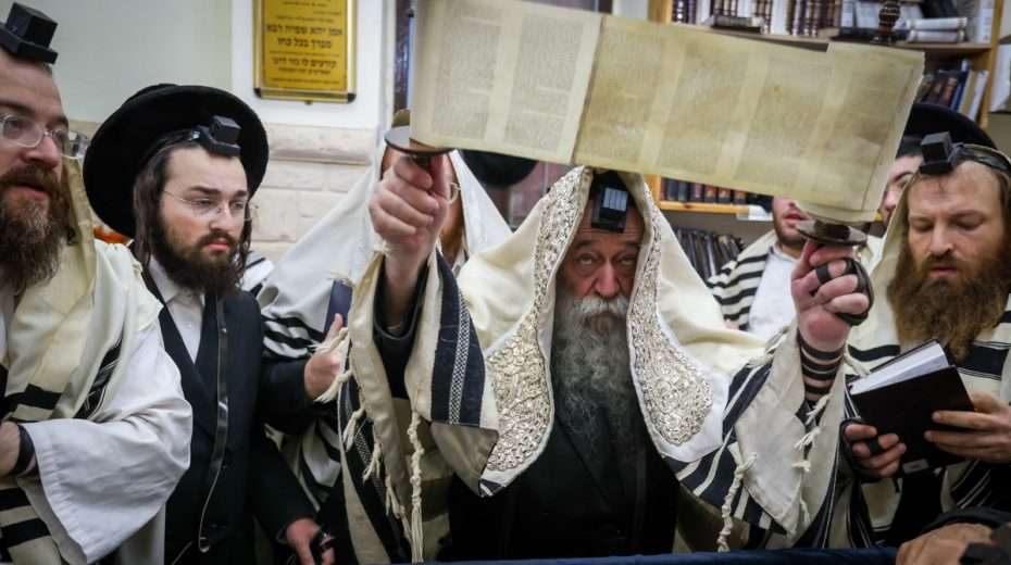 Ein Rabbiner hält während der täglichen Gebete im Norden Israels eine Torarolle.