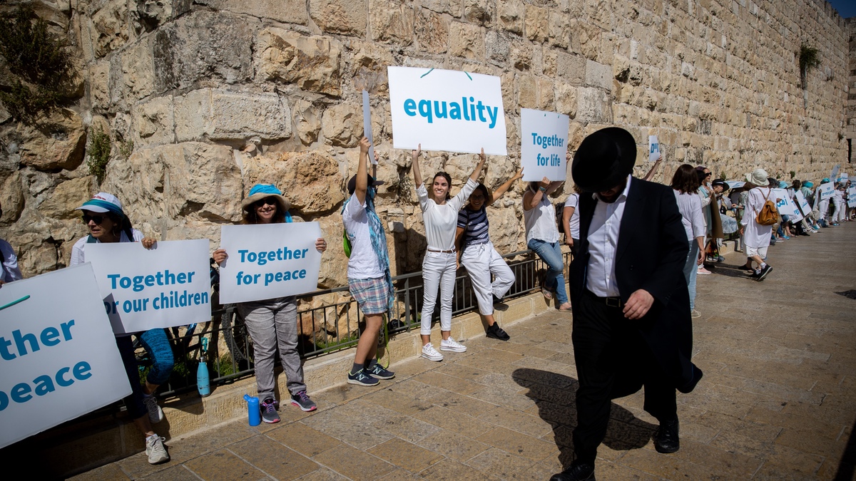 An Orthodox Jew tries to ignore liberal secular Israelis as he passes a demonstration.
