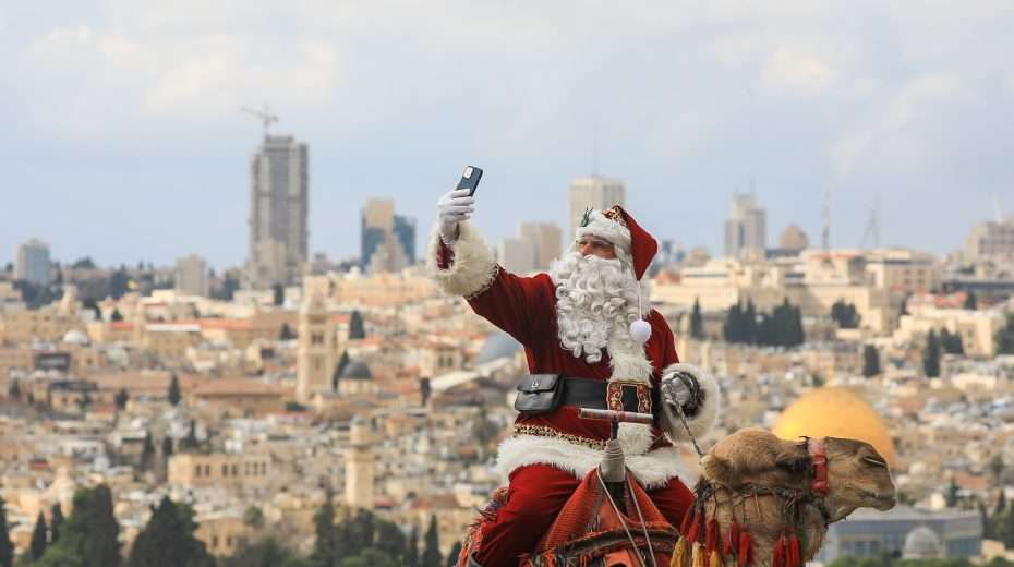 Der Weihnachtsmann, reitet auf einem Kamel auf dem Ölberg mit Blick auf die Altstadt Jerusalems