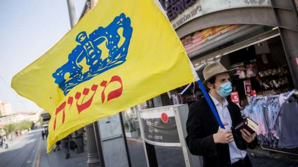 A Chabad disciple carries a flag reading "Messiah" through the streets of Jerusalem.