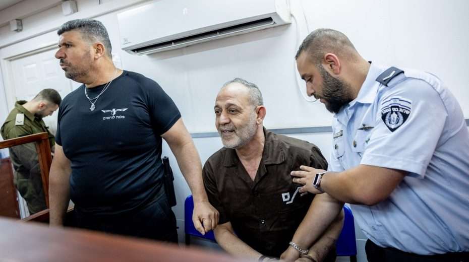 A blood-soaked Palestinian terrorist (center) smiles in court, knowing that Israel's lenient policies will afford him a relatively comfy stay in prison and likely an early release.