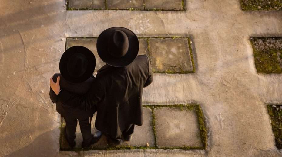 Zwei religiöse Juden stehen über dem Grab eines geliebten Menschen in Jerusalem.