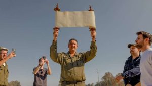 Israeli soldiers and civilians pray with a Torah scroll that survived the Holocaust at a staging area near the border with the Gaza Strip, December 21, 2023. Photo: Chen Schimmel/Flash90