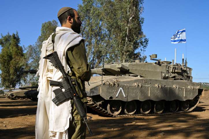 An Israeli soldier with a prayer shawl seen during a morning prayer near his tank near the border with Lebanon, northern Israel, October 25, 2023. Photo by Michael Giladi/Flash90