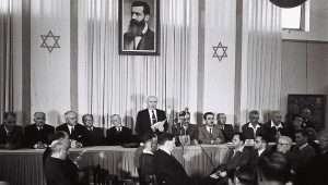 Israeli founding father and first prime minister David Ben-Gurion declares independence beneath a large portrait of Theodor Herzl, founder of modern Zionism, at the Tel Aviv Museum, today Independence Hall, on May 14, 1948. Photo by Zoltan Kluger/GPO.