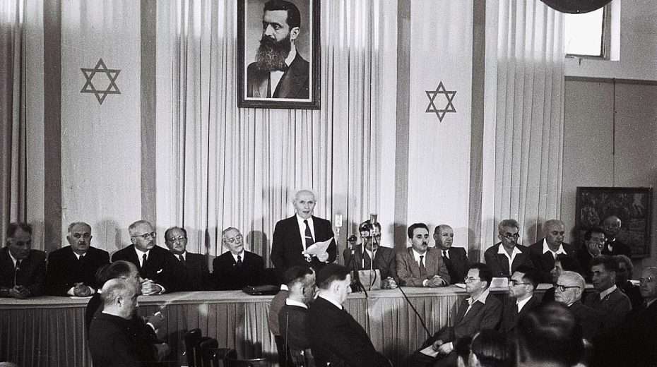 Israeli founding father and first prime minister David Ben-Gurion declares independence beneath a large portrait of Theodor Herzl, founder of modern Zionism, at the Tel Aviv Museum, today Independence Hall, on May 14, 1948. Photo by Zoltan Kluger/GPO.