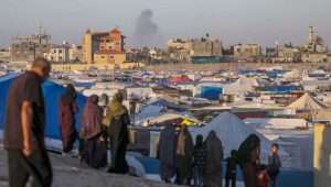 Palestinian refugees in a camp in Rafah in the southern Gaza Strip, as smoke rises in the background following an Israeli airstrike, May 7, 2024. Photo: EPA-EFE/MOHAMMED SABER