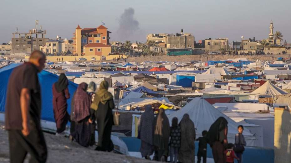 Palestinian refugees in a camp in Rafah in the southern Gaza Strip, as smoke rises in the background following an Israeli airstrike, May 7, 2024. Photo: EPA-EFE/MOHAMMED SABER