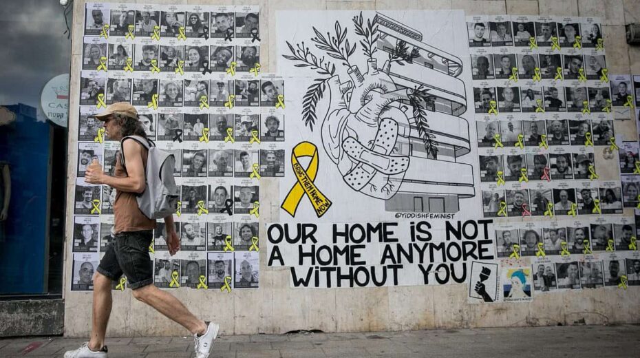 Israelis walk past a mural with photographs of Israelis held hostage by Hamas terrorists in the Gaza Strip since Oct. 7, in Tel Aviv, June 23, 2024. Photo by Miriam Alster/Flash90.