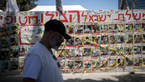 A man walks by photos of Israelis still being held hostage by Hamas terrorists in Gaza since Oct. 7, at "Hostage Square" in Tel Aviv on ,June 25, 2024. Photo by Miriam Alster/Flash90.