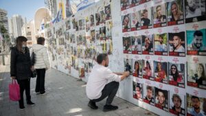 A man posts photographs of the Israelis still being held captive in the Gaza Strip by Hamas terrorists at "Hostages Square" in Tel Aviv on March 4, 2024. Photo by Miriam Alster/Flash90.