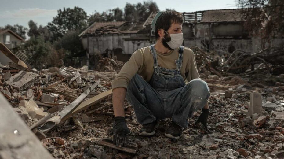 A man whose father was murdered by Hamas terrorists on Oct. 7 searches the rubble of his home for family mementos in Kibbutz Be'eri, Nov. 30, 2023. Photo by Chen Schimmel/Flash90.