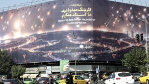 People walk past an anti-Israel billboard depicting Iran's missile attack on Israel, with a sentence in Persian: "If you want war, we are the masters of war," and in Hebrew below: "Israel must be wiped off the face of the earth," at Enqelab Square in Tehran, Iran, October 7, 2024. Photo: EPA-EFE/ABEDIN TAHERKENAREH