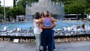 Israelis hug in Tel Aviv's Dizengoff Square next to photos of Israelis murdered in the October 7 massacre on the first anniversary of the Hamas attack. October 7, 2024, Photo: Tomer Neubergi/Flash90