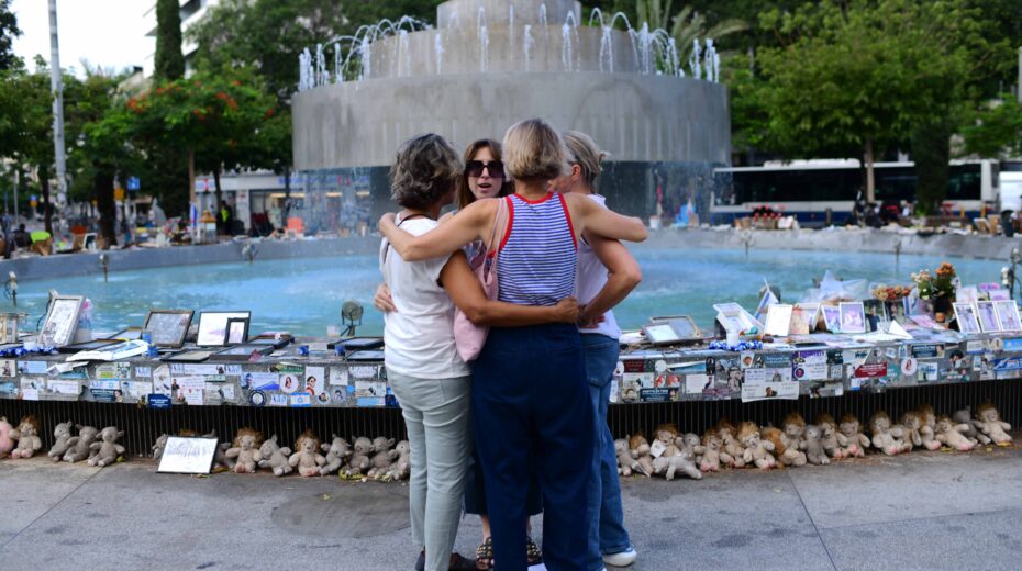Israelis hug in Tel Aviv's Dizengoff Square next to photos of Israelis murdered in the October 7 massacre on the first anniversary of the Hamas attack. October 7, 2024, Photo: Tomer Neubergi/Flash90