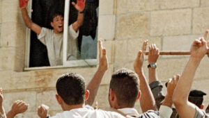 Aziz Salha, one of the participants in the 2000 lynching in Ramallah of two IDF reservists, holds up his blood-stained hands inside the Palestinian Authority's el-Bireh police station. Credit: Palestinian Media Watch.