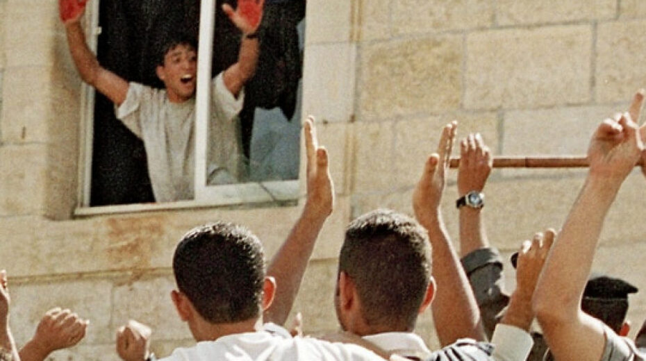Aziz Salha, one of the participants in the 2000 lynching in Ramallah of two IDF reservists, holds up his blood-stained hands inside the Palestinian Authority's el-Bireh police station. Credit: Palestinian Media Watch.