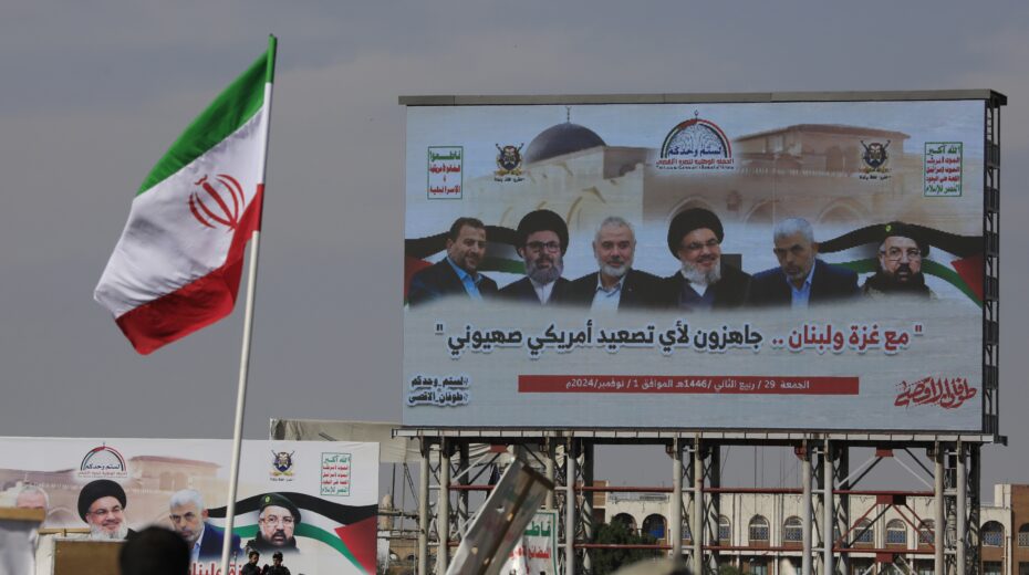 An Iranian flag flies in front of a poster depicting (from right to left) slain Hezbollah commander Fouad Shukur, slain Hamas leader Yahya Sinwar, slain Hezbollah leader Hassan Nasrallah, slain Hamas leader Ismail Haniyeh, slain Hezbollah Executive Council member Hashem Safieddine and slain Hamas leader Saleh al-Arouri, during a rally in Sanaa, Yemen, on November 1, 2024. Their addiction to destroying Israel cost them their lives. Photo: EPA-EFE/YAHYA ARHAB