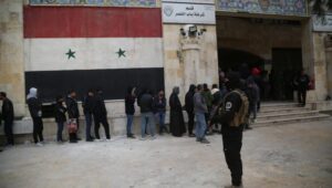 Opposition National Liberation rebels secure a former government building in Aleppo, Syria, on December 5, 2024, where people wait for their status registration after the opposition captured the city. Photo: EPA-EFE/BILAL AL ​​HAMMOUD