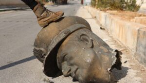 An opposition fighter steps on the beheaded statue of former Syrian President Hafez al-Assad at Mezzeh military airport in Damascus, Syria, December 12, 2024. Photo: EPA-EFE/MOHAMMED AL RIFAI