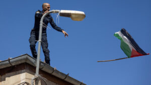 An Israeli police officer tosses a Palestinian flag off the top of a building in Jerusalem. Photo by Chaim Goldberg/Flash90