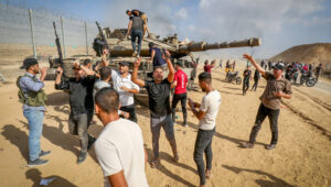Palestinians take control of an IDF tank after breaching the Israeli border fence from Khan Yunis in the southern Gaza Strip, Oct. 7, 2023. Photo by Abed Rahim Khatib/Flash90.