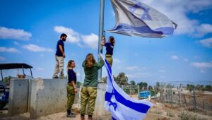 Israeli soldier hang an Israeli flag in Kibbutz Nir Am, near the Israeli border with the Gaza Strip, on Aug. 12, 2024. Photo by Avshalom Sassoni/Flash90.