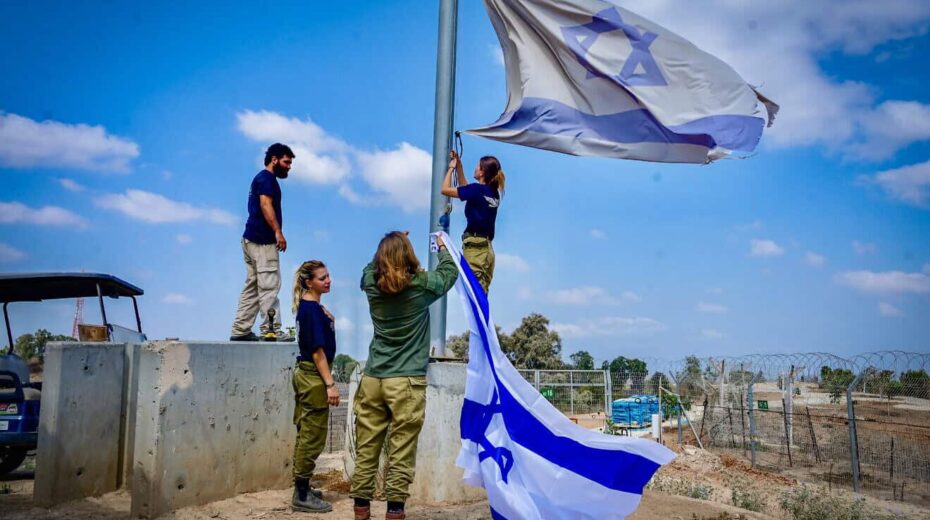 Israeli soldier hang an Israeli flag in Kibbutz Nir Am, near the Israeli border with the Gaza Strip, on Aug. 12, 2024. Photo by Avshalom Sassoni/Flash90.