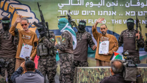 Hamas terrorists in its Al-Qassam Brigades parade Israeli hostages Eli Sharabi (right), Or Levy and Ohad Ben Ami (left) on a stage before handing them over to the International Red Cross, Feb 8, 2025. Photo by Abed Rahim Khatib/Flash90.