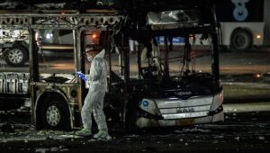 An investigator examines a bombed bus in Bat Yam, south of Tel Aviv, Feb. 20, 2025. Credit: Flash90.