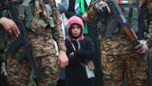 Hamas terrorists watch a propaganda ceremony during which Israeli hostages are turned over to the Red Cross, Gaza Strip, Feb. 22, 2025. Credit: Ali Hassan/Flash90.