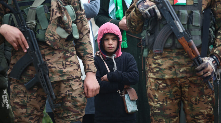 Hamas terrorists watch a propaganda ceremony during which Israeli hostages are turned over to the Red Cross, Gaza Strip, Feb. 22, 2025. Credit: Ali Hassan/Flash90.
