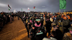 Members of Al-Qassam Brigades, the Hamas military wing, stand guard while Palestinians wait to hand over the bodies of four late Israeli hostages to the Red Cross, as part of the ceasefire agreement between Israel and Hamas, in Khan Yunis in the southern Gaza Strip, Feb. 20, 2025. Saeed Mohammed/Flash90.
