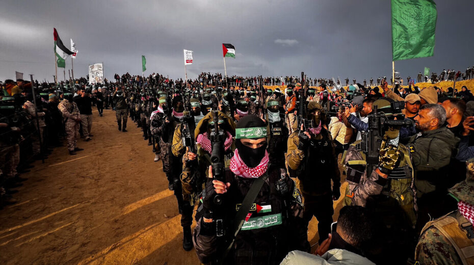 Members of Al-Qassam Brigades, the Hamas military wing, stand guard while Palestinians wait to hand over the bodies of four late Israeli hostages to the Red Cross, as part of the ceasefire agreement between Israel and Hamas, in Khan Yunis in the southern Gaza Strip, Feb. 20, 2025. Saeed Mohammed/Flash90.