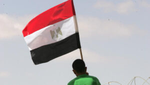 A Palestinian man raises an Egyptian flag at the Sinai-Gaza border. Photo by Abed Rahim Khatib/Flash90
