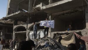 A boy holds a banner reading "Enough destroyed, enough killed, we want to live" during a demonstration in Beit Lahia in the northern Gaza Strip. Photo: EPA-EFE/HAITHAM IMAD