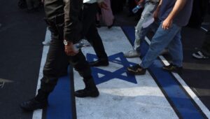 Iranians walk over an image of an Israeli flag during an anti-Israel rally in Tehran, Iran, on June 14, 2025. Photo: EPA-EFE/ABEDIN TAHERKENAREH