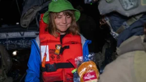 An Israeli soldier offers food and water to activist Greta Thunberg wearing a life jacket and frog hat aboard the intercepted Gaza-bound yacht. Credit: Israel Foreign Ministry.