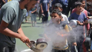 Palestinian children receive meals from volunteers in Gaza City, on May 29, 2025. Photo by Ali Hassan/Flash90.