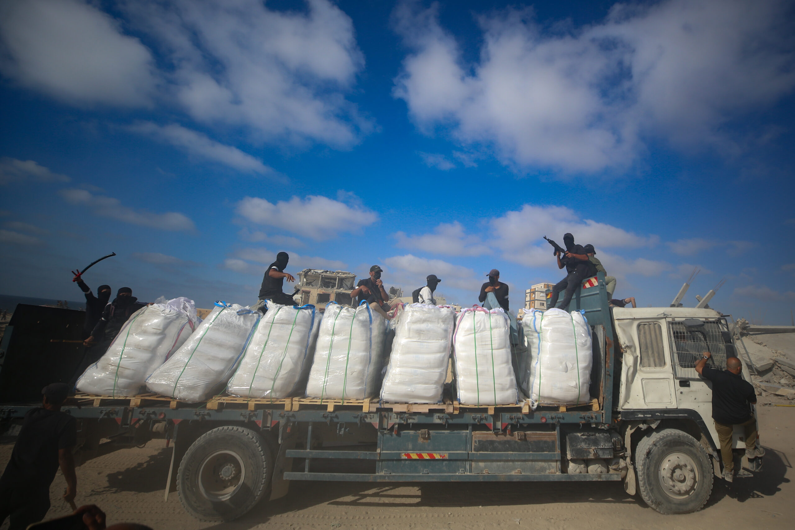 Armed Palestinians sit on a truck carrying humanitarian aid near the Zikim border crossing between Israel and Beit Lahia in the northern Gaza Strip. Photo: Ali Qariqa/Flash90, June 25, 2025.