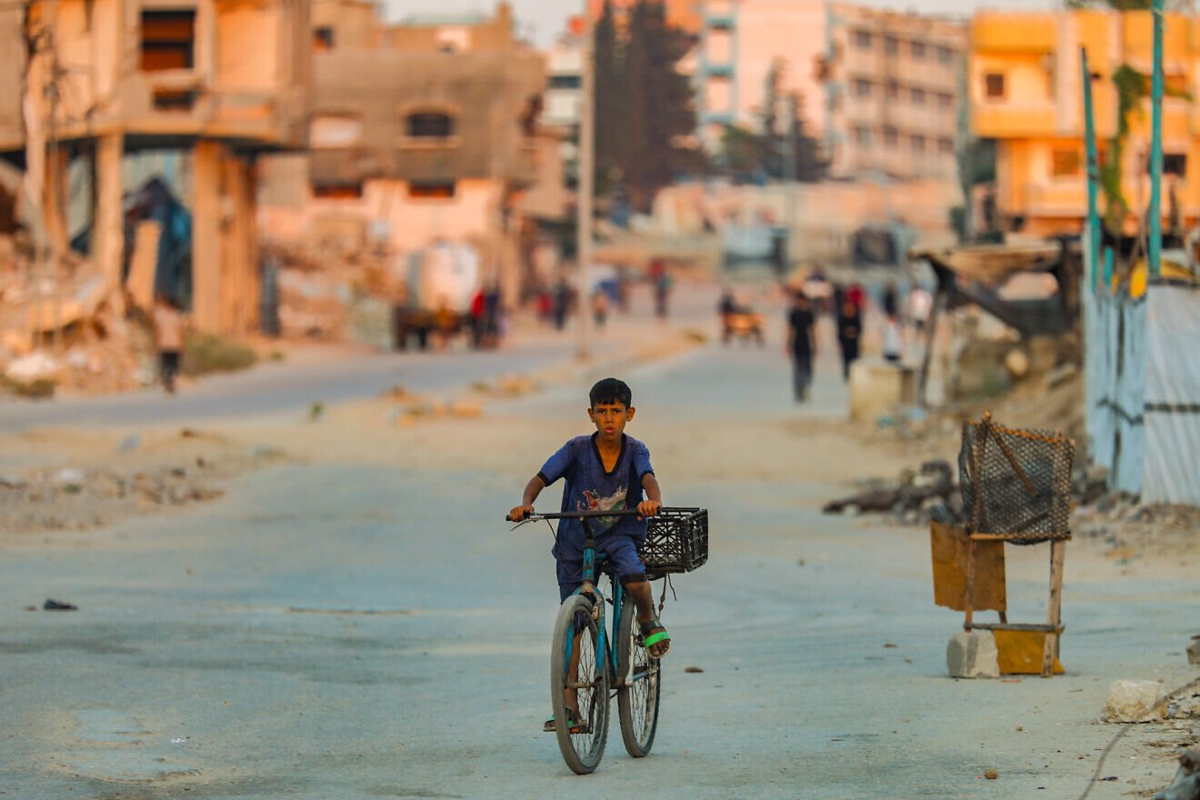 A Palestinian boy rides his bike at sunset in Al-Bureij refugee camp in the central Gaza Strip, July 22, 2025. Photo by Ali Hassan/Flash90.