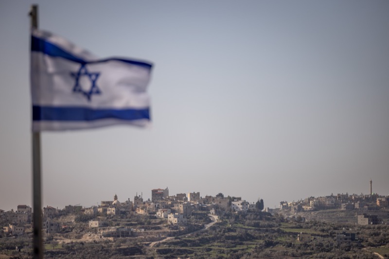 An Israeli flag in the Israeli community of Kedumim is seen in the foreground of a Palestinian village in Samaria. January 7 2025. Photo by Chaim Goldberg/Flash90