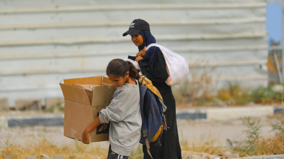 Palestinians carry food parcels and supplies from a GHF humanitarian aid distribution site in the Netzarim Corridor in central Gaza, August 8, 2025. Photo: Ali Hassan/Flash90