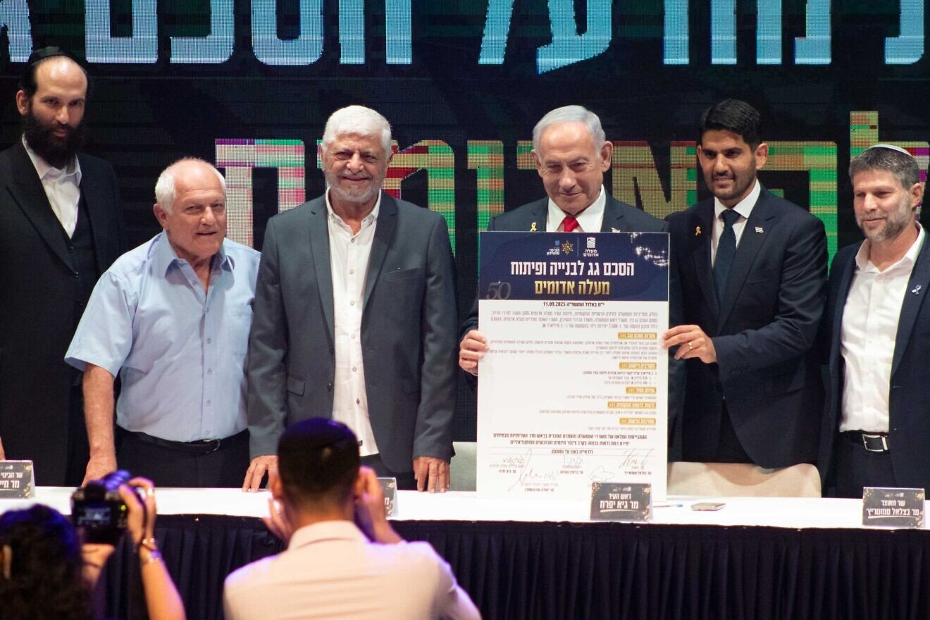 Prime Minister Benjamin Netanyahu holds up the umbrella agreement at a signing ceremony at the Ma'ale Adumim Cultural Center, flanked from left by the Construction and Housing Ministry's Director-General Yehuda Morgenstern and Minister Haim Katz, former Ma'ale Adumim Mayor Benny Kashriel, current Ma'ale Adumim Mayor Guy Yifrach and Finance Minister Bezalel Smotrich, Sept, 11, 2025. Photo by David Isaac.